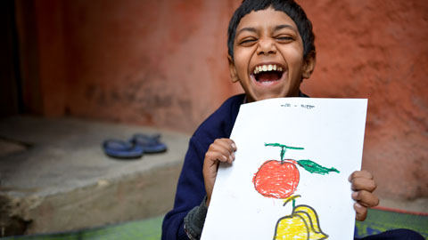 How it works to sponsor a child. Step 1, Choose a child to sponsor, like this little boy in India. Bedal age 9, proudly holds a drawing.